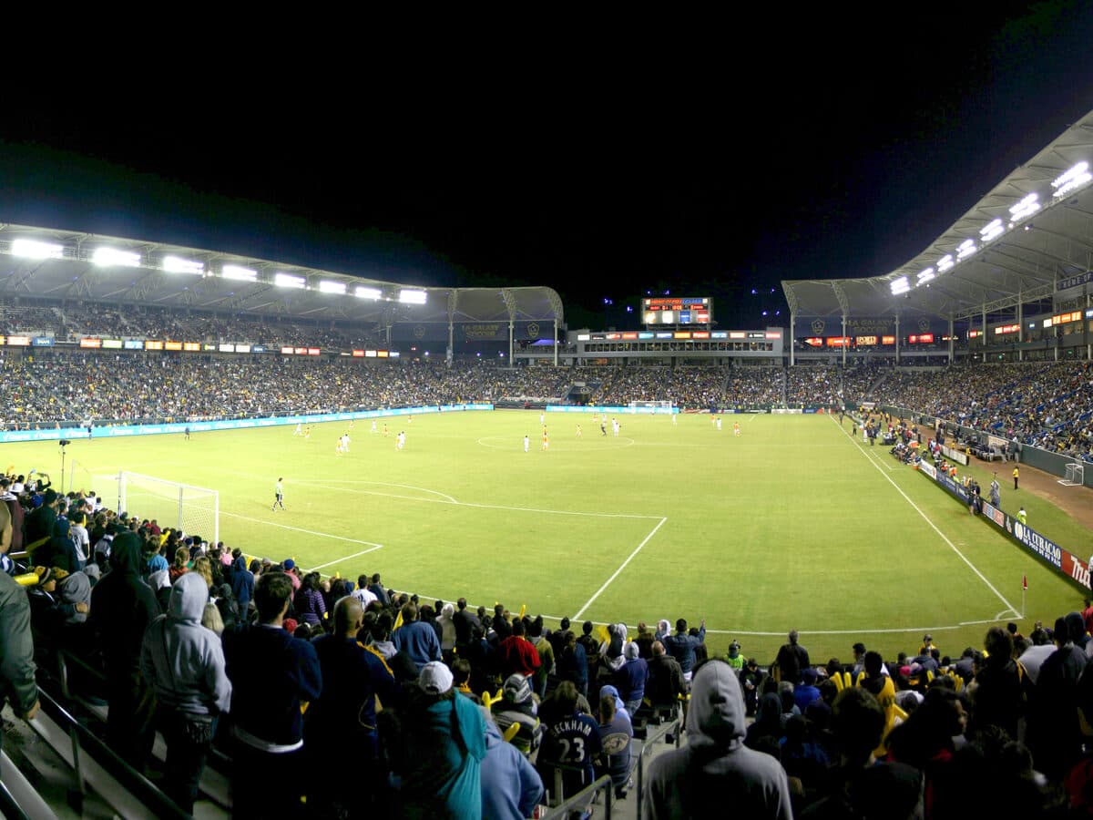 Fans watching a soccer match from the stands under stadium floodlights