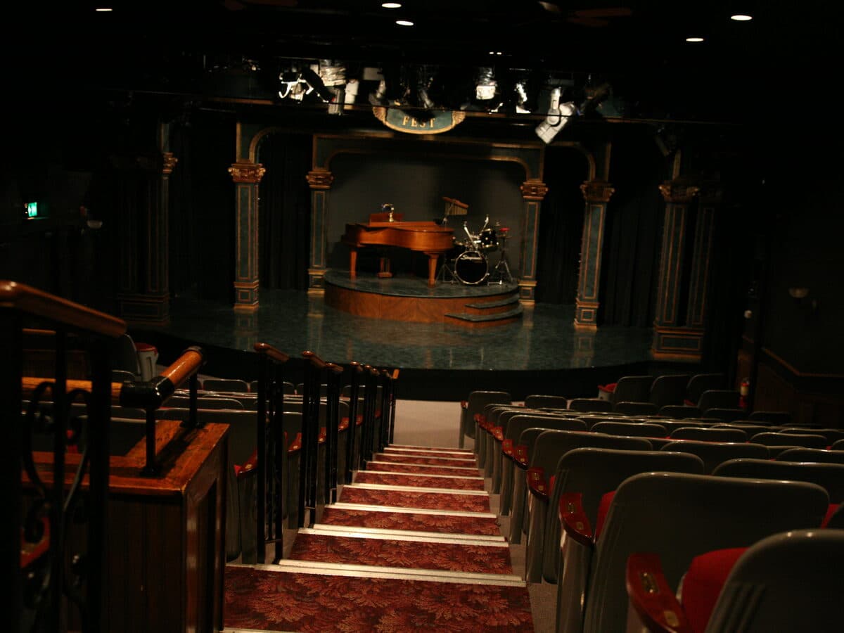 Rows of empty seats facing a small, ornate theatre stage