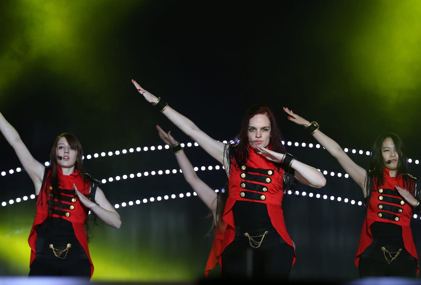 Performers mid-routine on stage under green stage lighting