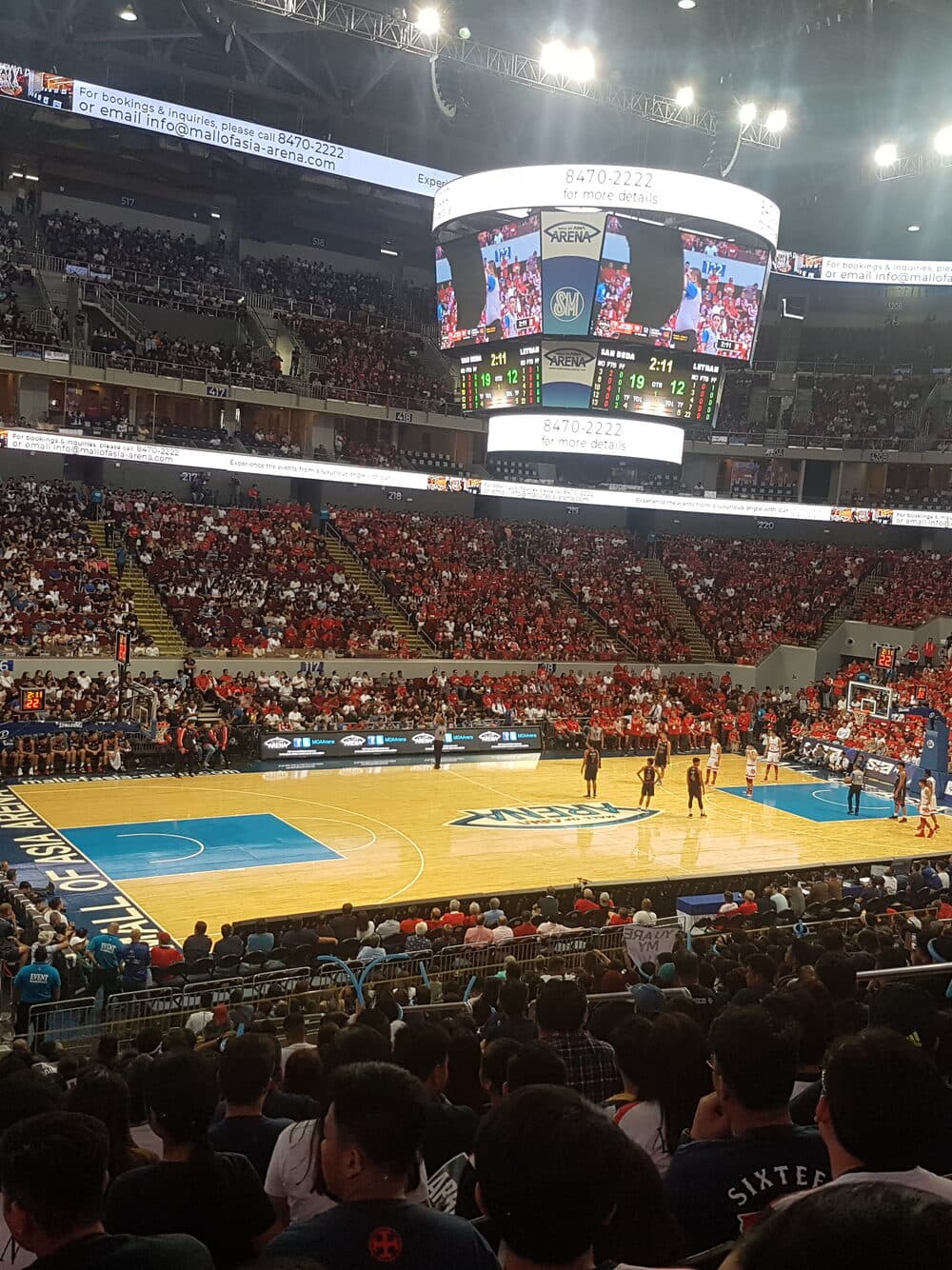 A packed arena watching a basketball game from the lower bowl